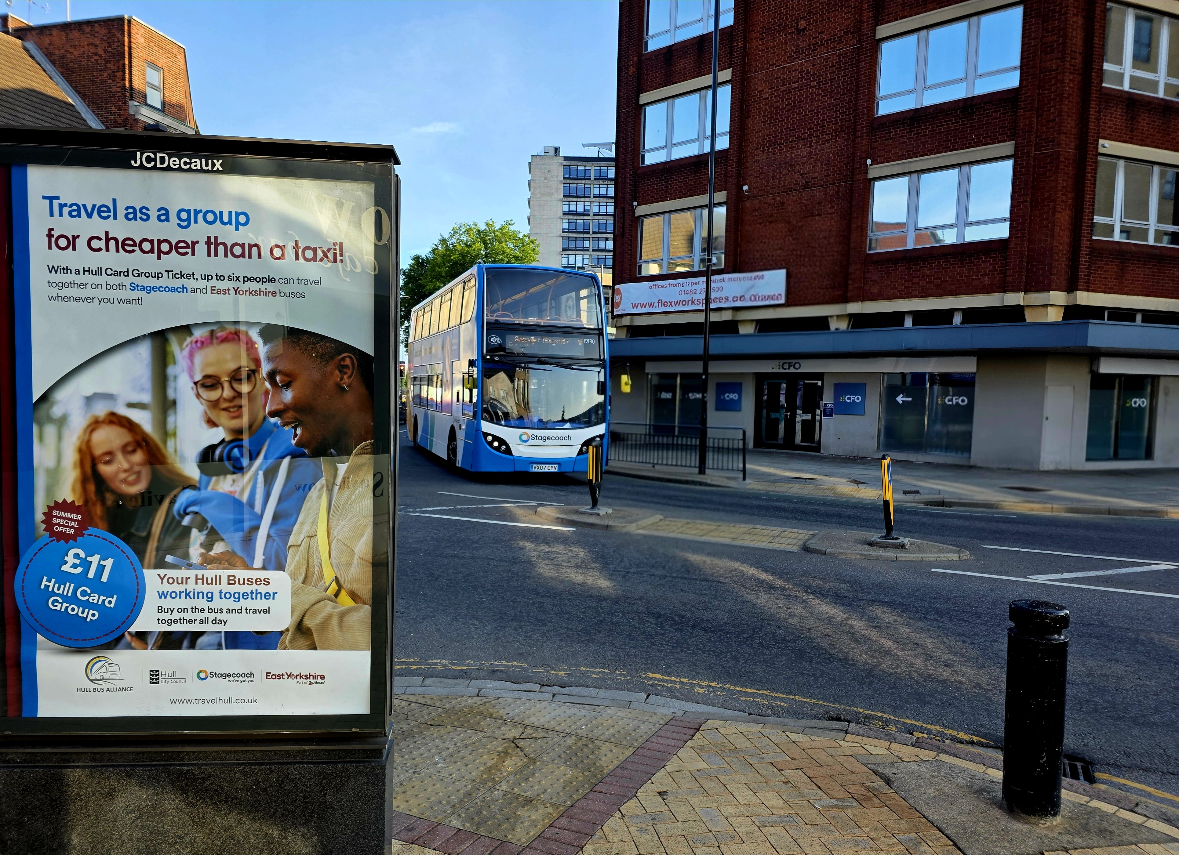 A Stagecoach East Midlands service passing through Hull City Centre with an outdoor advertising hoarding promoting the August group travel discount