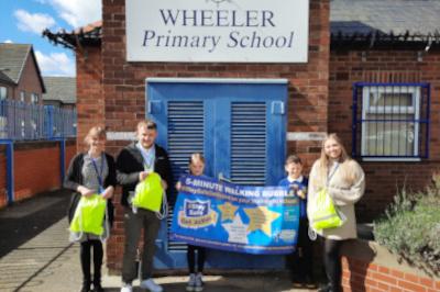 children and adults standing outside wheeler primary school