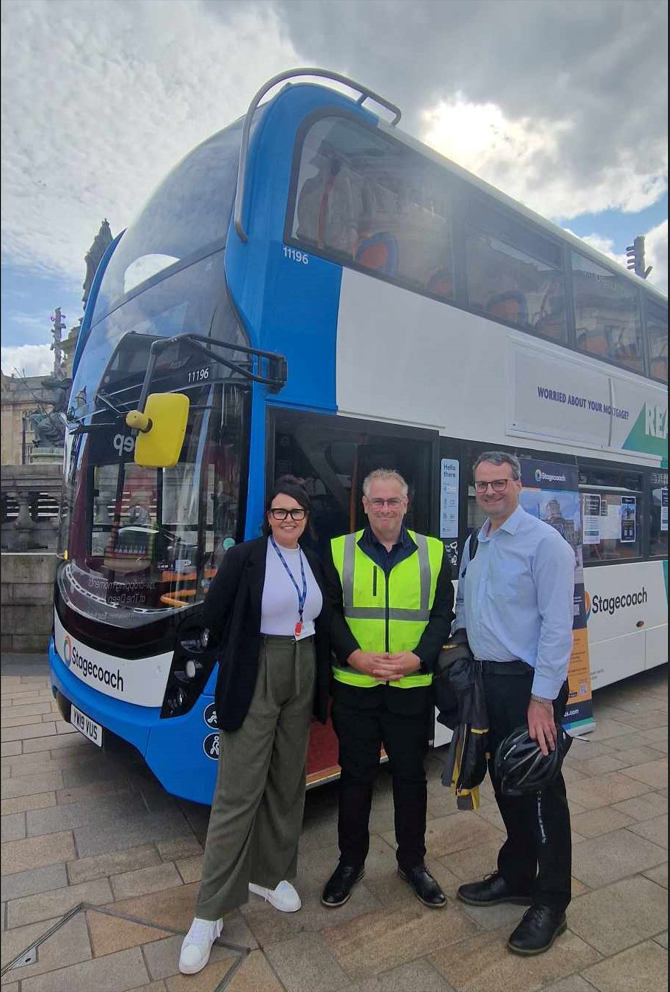 Three people standing besides a bus