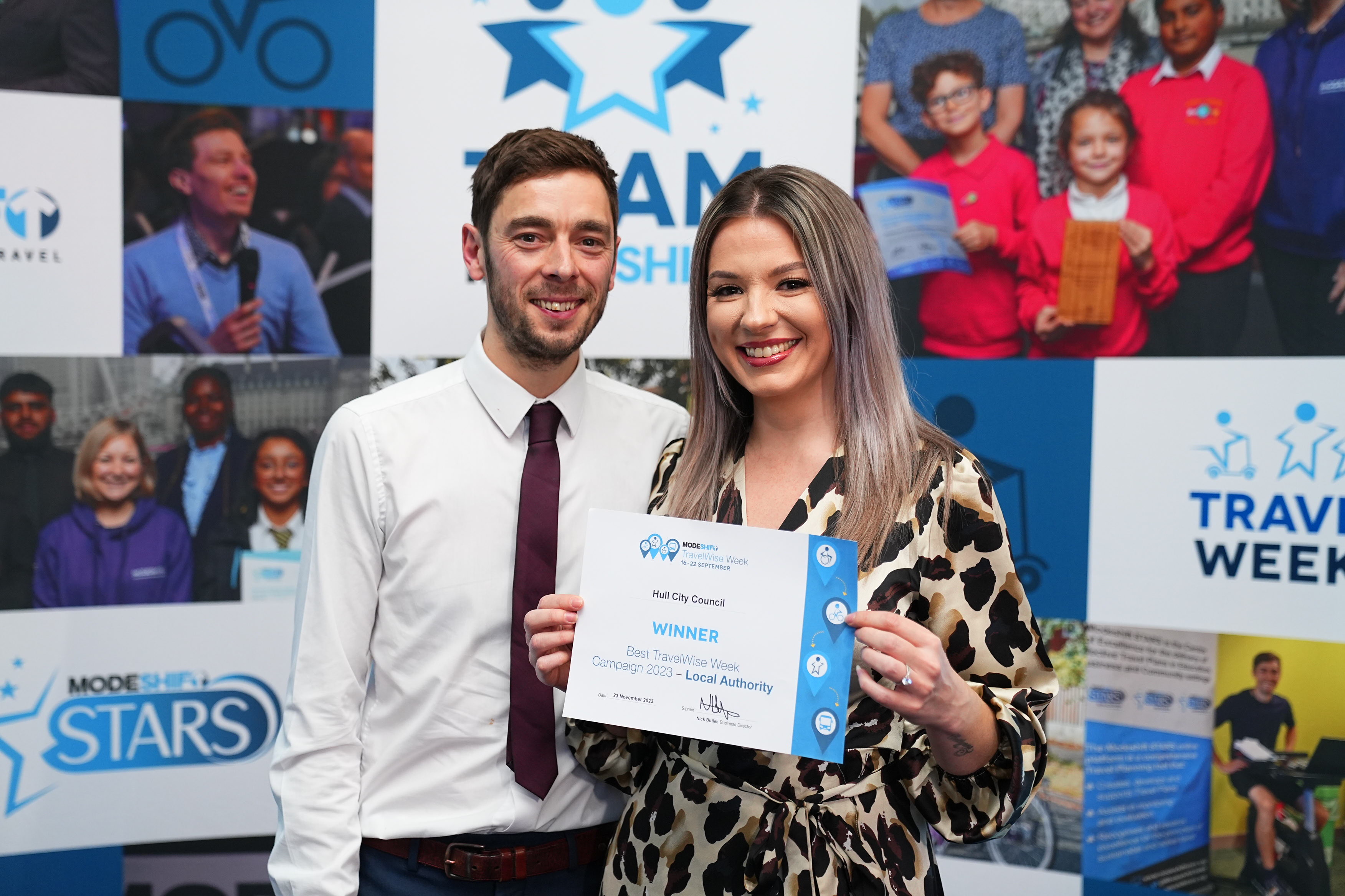 A photograph of 2 people holding an awards certificate.