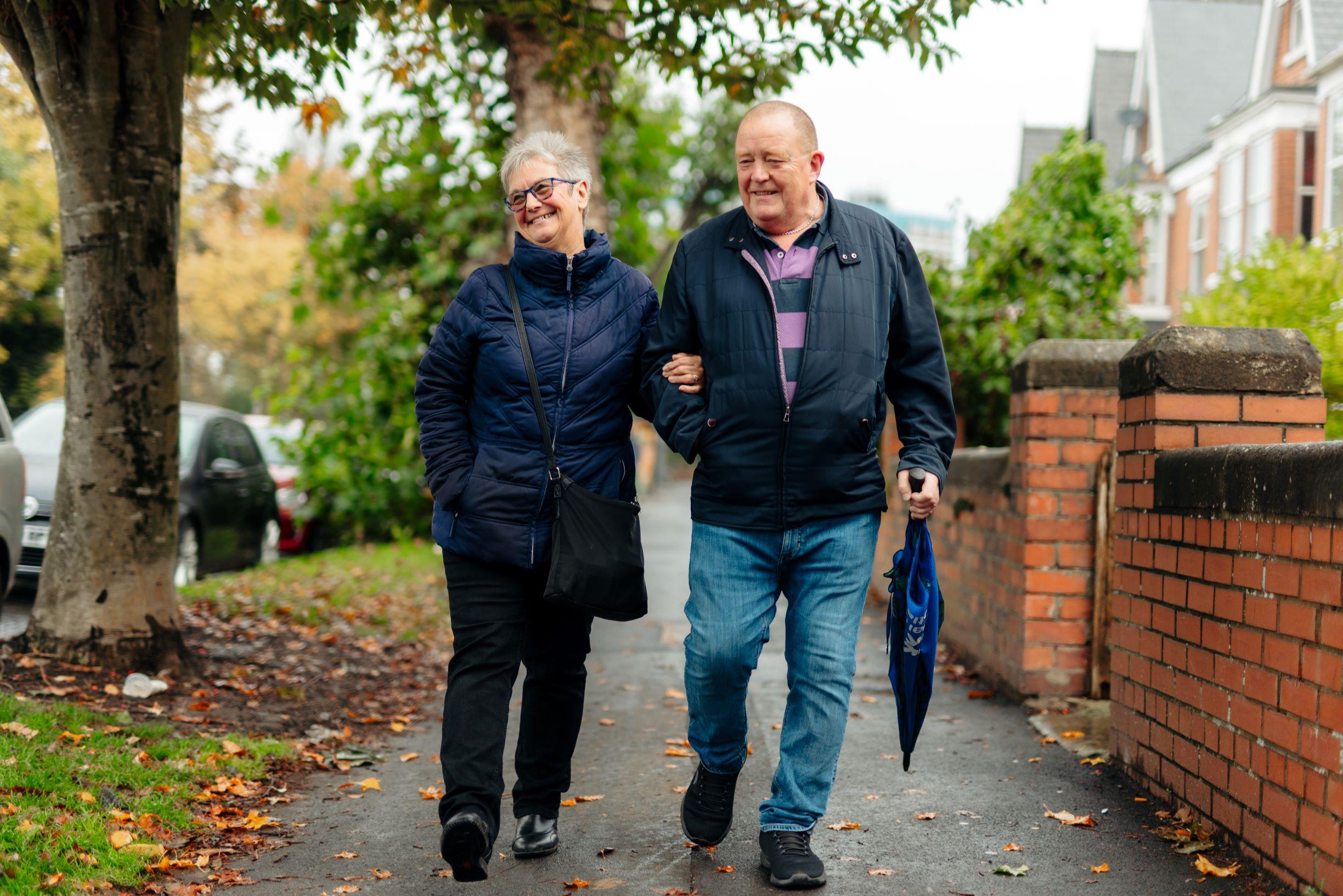 Photograph of 2 people walking together down a street.